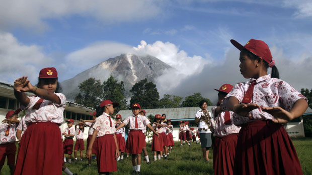 <p>Em Karo, na Indonésia, estudantes fazem exercícios com erupção do Monte Sinabung ao fundo</p>