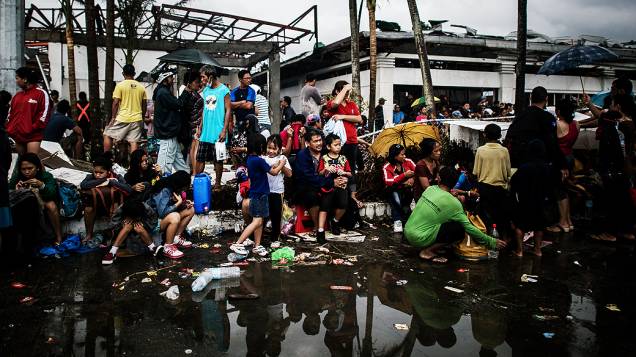 Moradores esperam por comida no aeroporto de Tacloban, nas Filipinas
