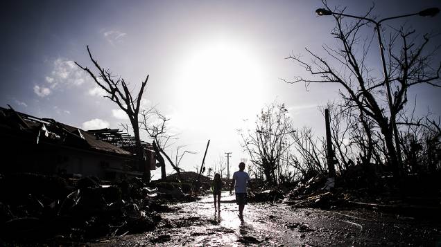 Sobreviventes percorrem as ruínas de um bairro afetado pelo tufão nos arredores de Tacloban, nas Filipinas