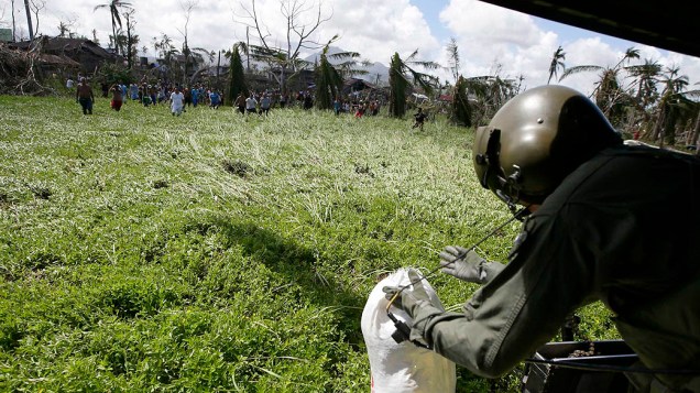 Sobreviventes tentam pegar comida distribuída pelos soldados filipinos nos arredores da cidade de Tacloban