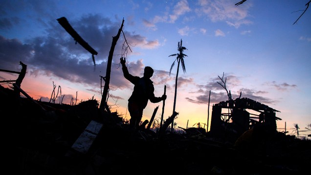 Homem entre os destroços de um bairro arruinado pela passagem do supertufão Haiyan na cidade Palo Leyte, nas Filipinas