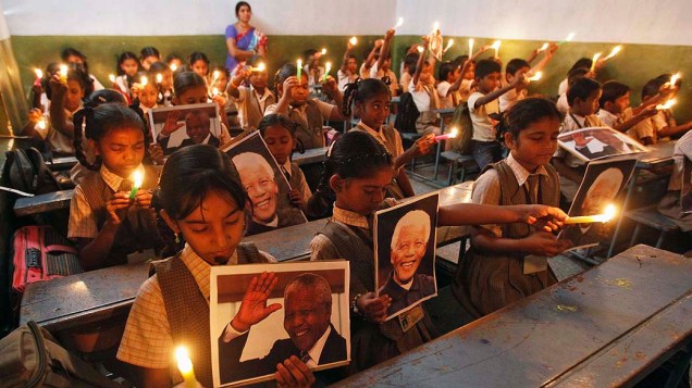 Crianças seguram velas e retratos de Nelson Mandela enquanto fazem oração em cerimônia em uma escola de Ahmedabad, na Índia, em homenagem ao líder sul-africano