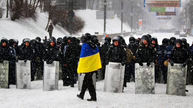 Manifestante observa policiais na praça da Independência, em Kiev (Ucrânia)
