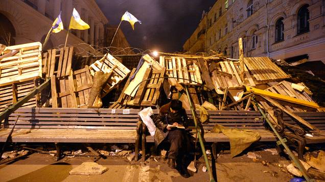 Um manifestante lê na madrugada desta segunda-feira (9) enquanto guarda barricada de protesto, na praça da Independência, em Kiev (Ucrânia)