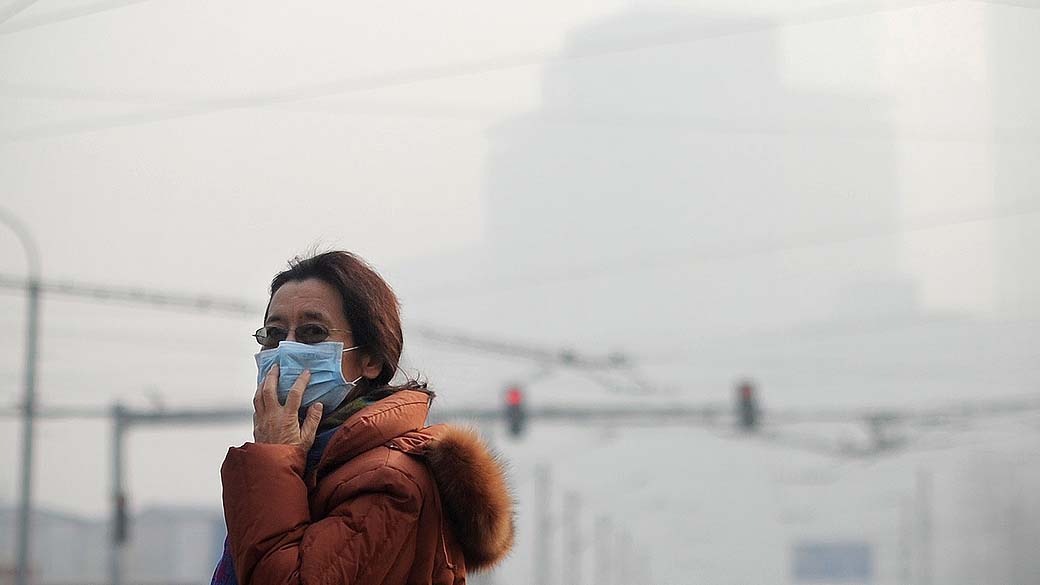 Mulher usa máscara para se proteger da poluição em um dia cinzento em Pequim, na China