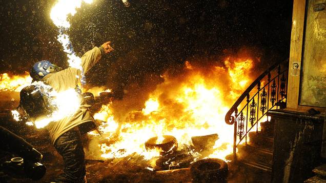 Manifestante lança coquetel molotov em confronto com a polícia durante protesto contra o governo em Kiev, na Ucrânia
