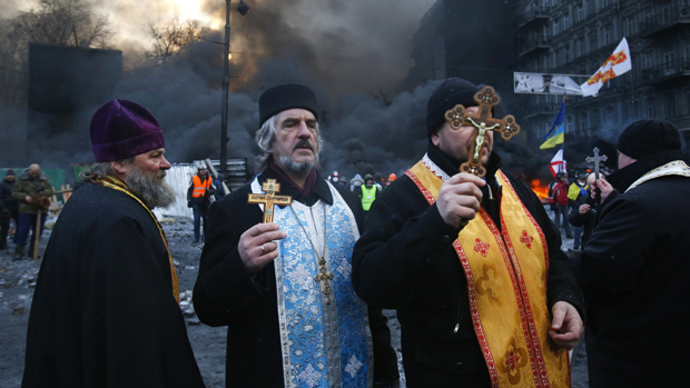 Sacerdotes de diferentes religiões rezam durante confrontos com a polícia no centro de Kiev, Ucrânia