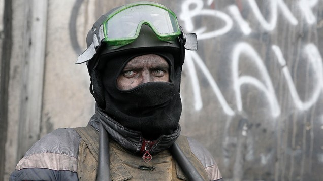 Manifestante guarda as barricadas em frente da polícia anti-motim em Kiev, Ucrânia