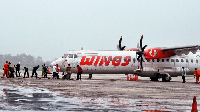 Funcionários trabalham em avião coberto de cinzas e areia, no aeroporto Adi Sucipto, em Yogyakarta (Indonésia)