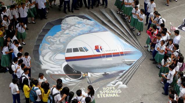 <p>Estudantes se reúnem em torno de obra de arte tridimensional, baseada no voo 370 da Malaysia Airlines, desaparecido desde 8 de março, pintada em Makati (Filipinas)</p>