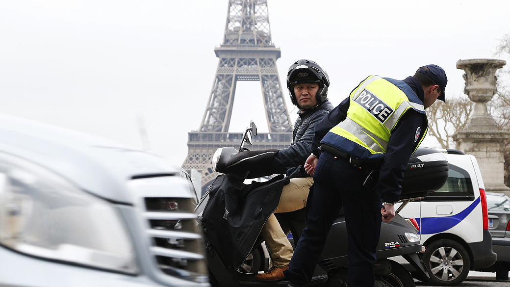 Policiais controlam passagem de veículos e motos em frente à Torre Eiffel, em Paris. A cidade recorreu a medidas drásticas para conter a alta dos níveis de poluição fazendo um rodízio de carros