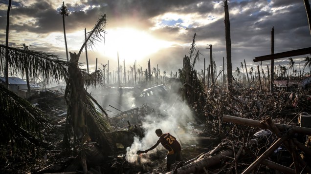 Homem tenta apagar um pequeno foco de incêndio em meio à destruição causada pela passagem do supertufão Haiyan em Leyte, nas Filipinas