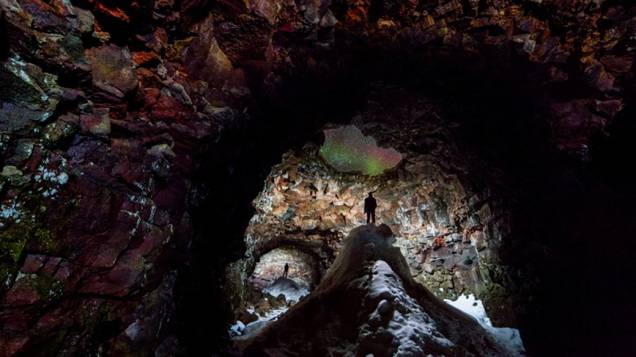 <p>Imagem feita em uma caverna de lava de 1.300 metros na Islândia. O teto cedeu em algumas partes, o que faz com que a neve se  acumule lá dentro durante o inverno. Um buraco no telhado, na parte superior da foto, revela uma aurora boreal no céu</p>