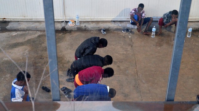 Imigrantes detentos rezam no abrigo temporário em Lampedusa