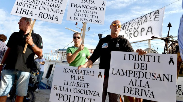 Ativistas protestam do lado de fora do aeroporto de Lampedusa, durante a visita de Manuel Barroso, Presidente da Comissão Europeia