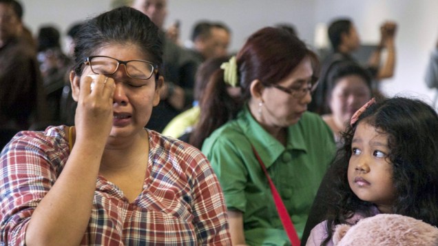 Familiares de passageiros do avião da AirAsia no aeroporto de Surabaya na Indonesia