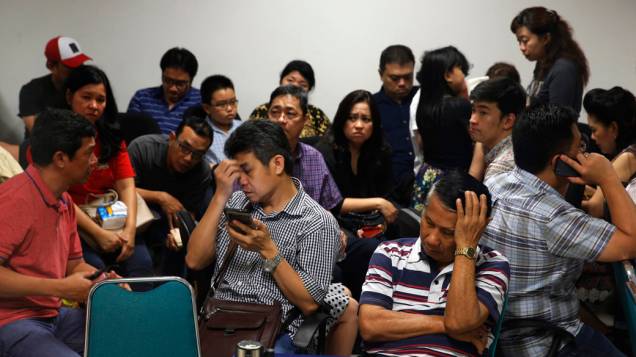 Familiares de passageiros do avião da AirAsia no aeroporto de Surabaya na Indonesia