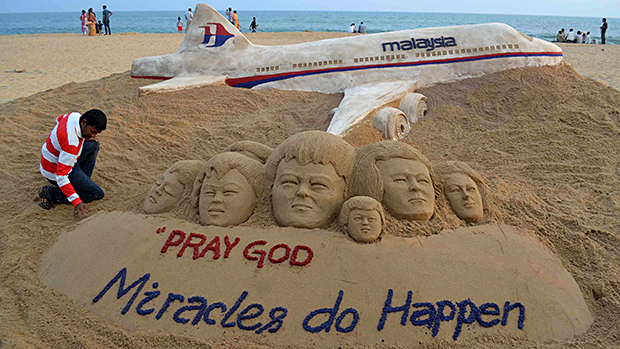 Artista indiano Sudarshan Patnaik faz os retoques finais em uma escultura de areia que ele criou desejando o bem-estar dos passageiros do voo MH370 da Malaysia Airlines, em uma praia na cidade de Puri, na Índia