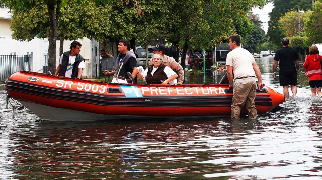 Bombeiros argentinos resgatam mulher de sua casa inundada após fortes chuvas que inundaram grande parte da cidade, em La Plata, Argentina