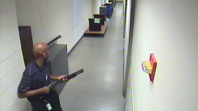 Alexis Aaron caminhando pelos corredores do prédio da Marinha carregando uma escopeta Remington 870. Ao abrir fogo, ele fez doze vítimas, antes de ser morto pela polícia.