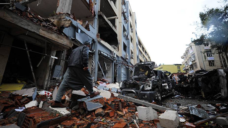 Homem caminha entre os escombros de uma rua onde um carro-bomba explodiu, em Reyhanli, em Hatay, a poucos quilômetros da fronteira com a principal passagem para a Síria, na Turquia
