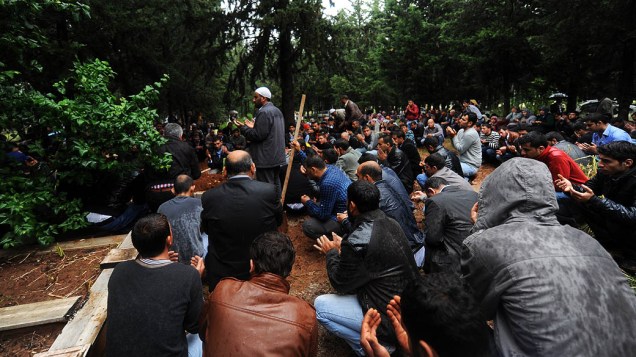 Homens fazem orações nas sepulturas das vítimas de um carro-bomba que explodiu em Hatay apenas alguns quilômetros da principal passagem de fronteira para a Síria