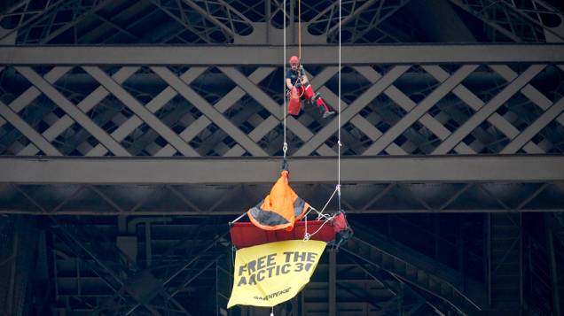 Bombeiro se aproxima de um ativista do Greenpeace pendurado no segundo andar da Torre Eiffel, que protestava contra as 30 pessoas detidas na Rússia após uma manifestação do grupo