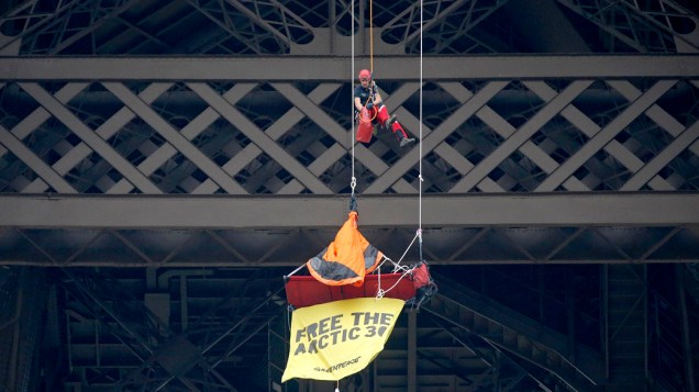 Bombeiro se aproxima de um ativista do Greenpeace pendurado no segundo andar da Torre Eiffel, que protestava contra as 30 pessoas detidas na Rússia após uma manifestação do grupo Bombeiro se aproxima de um ativista do Greenpeace pendurado no segundo andar da Torre Eiffel, que protestava contra as 30 pessoas detidas na Rússia após uma manifestação do grupo