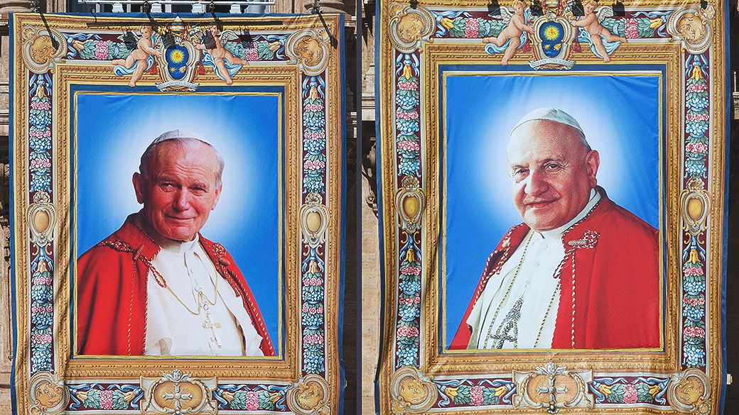 Tapeçarias com as imagens de João Paulo II e João XXIII expostas na fachada da Basílica de São Pedro no Vaticano