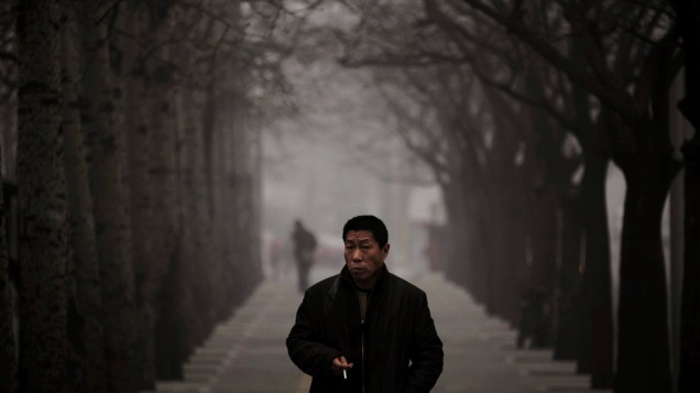 Homem anda ao longo de uma rua em dia nebuloso em Pequim, China