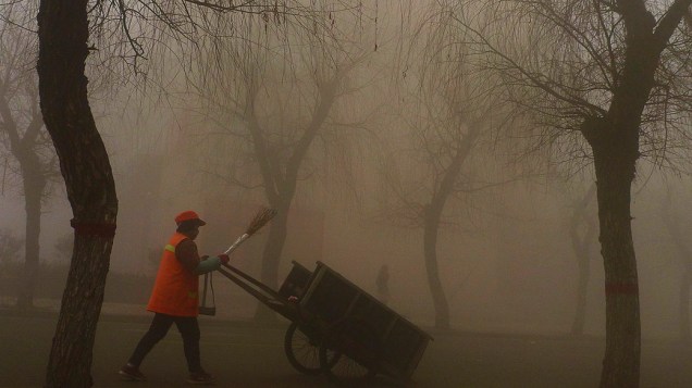 Trabalhador chinês em um parque de Pequim, vestindo máscara para se proteger da poluição, na manhã desta quarta-feira (30)