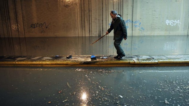 Funcionário municipal caminha em estrada inundada no centro de Atenas, Grécia