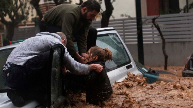 Mulher é resgatada por um morador em cima de seu carro durante inundação em Chalandri, Grécia