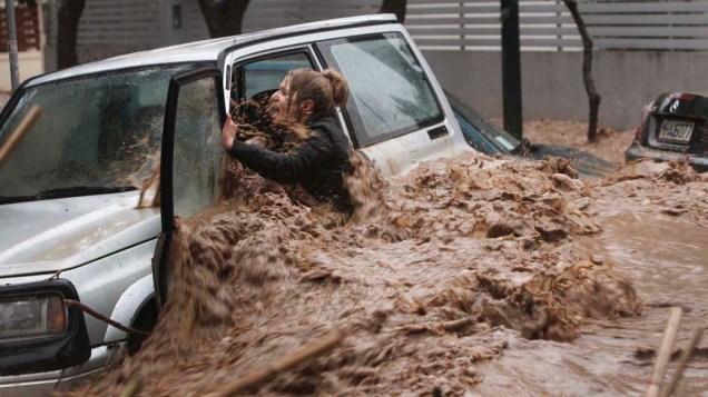Mulher segura em seu carro antes de ser resgatada por morador durante inundação em Chalandri, Grécia