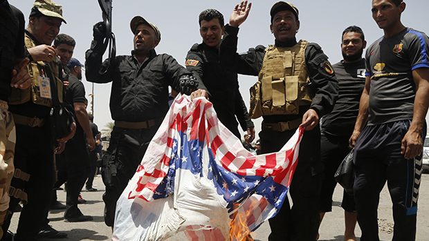 Milicianos xiitas convocados pelo clérigo radical Moqtada al-Sadr queimam bandeira americana durante marcha em Bagdá