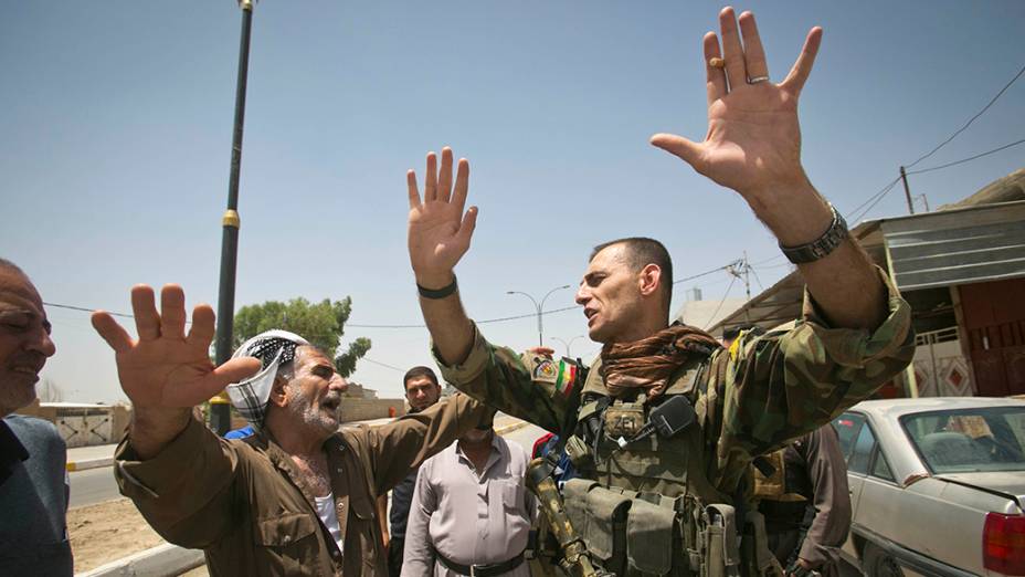 Soldado das forças curdas Peshmerga fala com um líder de uma comunidade xiita local, que elogia ações das Forças Especiais curdos para protegê-los de militantes sunitas liderados pelo Estado Islâmico do Iraque e do Levante (ISIL), na cidade de Kirkuk