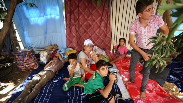 Cristãos iraquianos que fugiram da violência da cidade de Qaraqosh descansam próximo à uma Igreja, no iraque