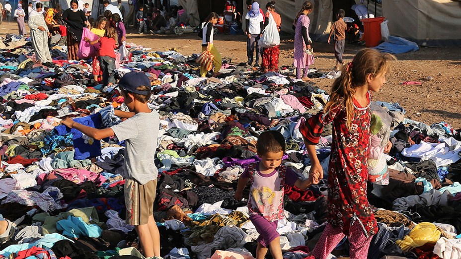 Iraquianos desabrigados recebem doações de roupas, na Síria