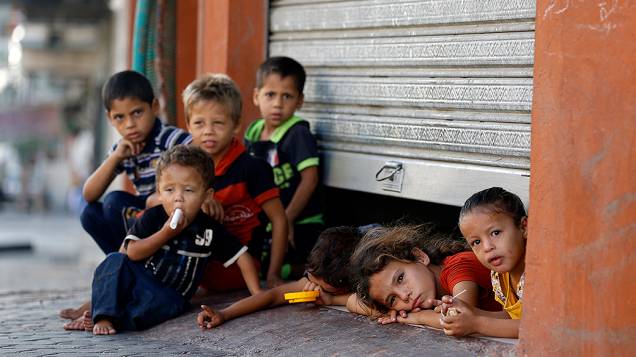 Crianças palestinas fotografadas debaixo da porta de uma loja onde estão abrigadas com sua família, na cidade de Gaza - 26/07/2014