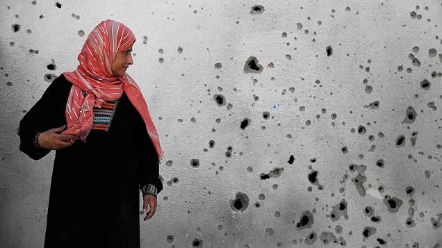 Mulher olha para uma parede com marcas de estilhaços após um ataque aéreo israelense no hospital de Beit Hanoun, em Gaza