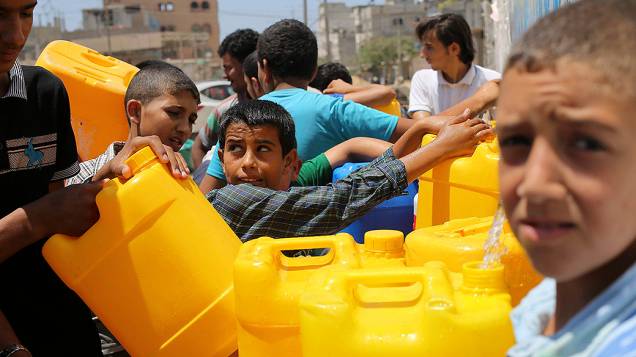 Palestinos enchem recipientes com água em torneiras públicas em Khan Younis, no sul da Faixa de Gaza