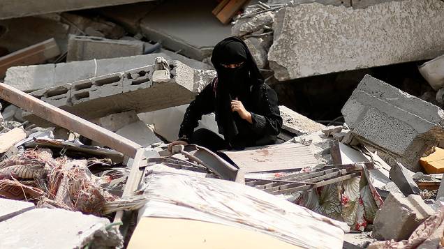 Menina palestina procura por seus pertences entre os destroços de sua casa, na Faixa de Gaza
