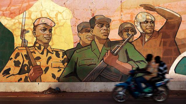 Motociclista passa em frente a mural pintado com desenho representando as forças do Mali, na capital Bamako