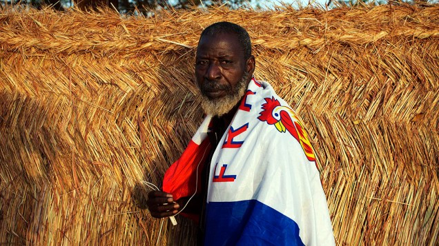 Homem com uma bandeira com o nome da França sobre os ombros durante intervenção francesa no Mali