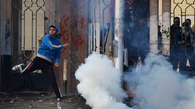Um estudante da Universidade Al-Azhar, defensor da Irmandade Muçulmana e do presidente deposto Mohamed Mursi, joga uma pedra durante confrontos com a polícia e moradores no distrito de Nasr City, no Cairo - (27/12/2013)