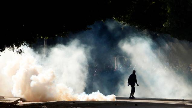 Manifestantes são vistos através da fumaça de bombas de gás lacrimogêneo usadas pela polícia durante os confrontos em Alexandria, nesta sexta feira (25)