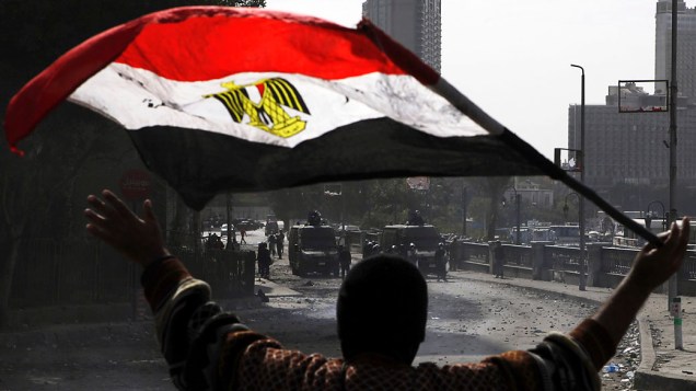 Manifestante conduz bandeira do Egito durante confrontos ao longo da ponte Qasr Al Nil, Cairo