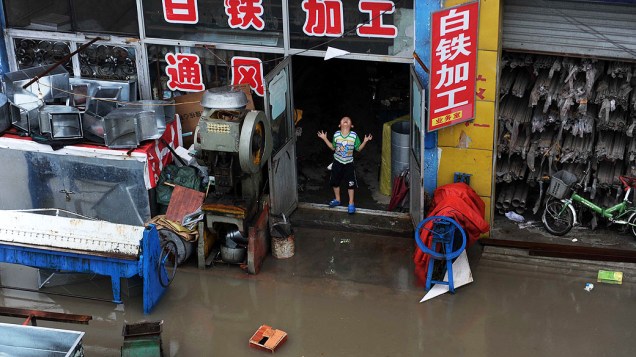 Criança chora ao lado de uma rua alagada, em Pequim. Pelo menos 295 pessoas foram mortas ou desaparecidas após chuvas e o Tufão Soulik atingir a China