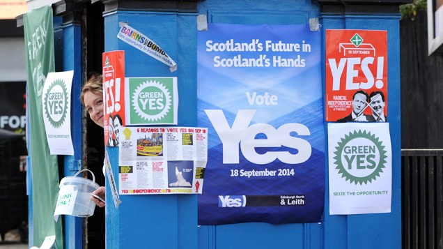 Partidária pela independência da Escócia pendura cartazes em sua banca, em Edimburgo