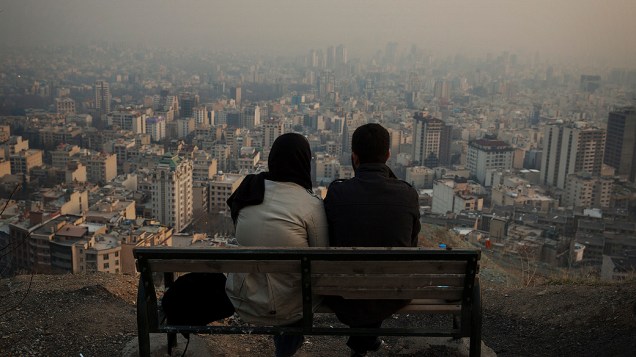 Um casal olha a cidade de Teerã do alto de uma colina, no Irã